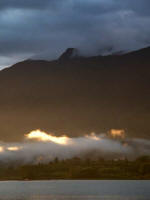 Sunlight beams begin suffusing the valley's cloud blanket.